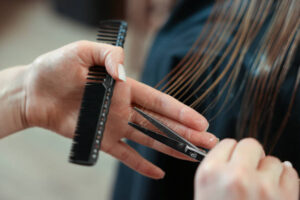 Professional hairdresser cutting girl's hair in beauty salon, closeup